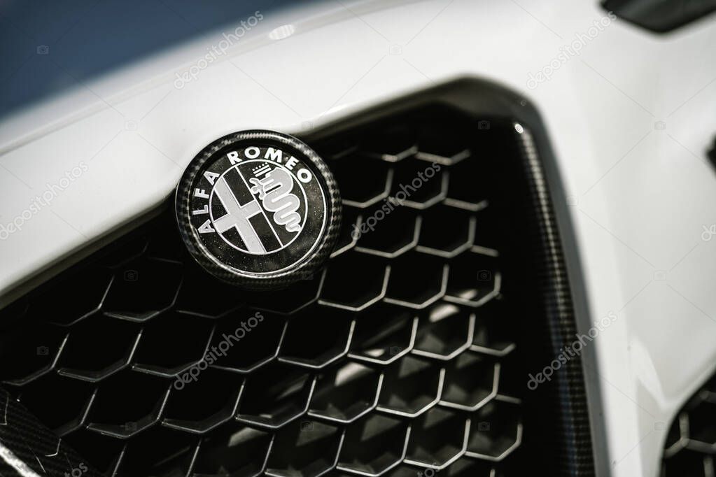 Milan, italy 20 september 2025: alfa romeo logo displayed on the front grille of a modern white luxury car, featuring a carbon fiber bezel and honeycomb pattern