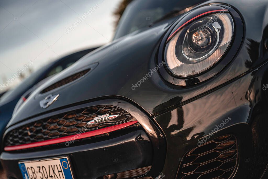 Milan, italy 20 september 2025: mini cooper john cooper works parked outdoors, close-up on headlight, hexagonal grille and red accent, showcasing sporty british design and compact performance characte