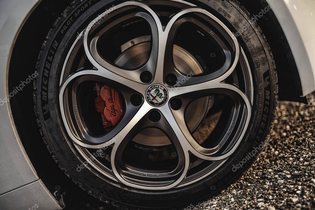 Milan, italy 20 september 2025: alfa romeo giulia wheel, rim, and red brake caliper showing automotive performance, engineering, and tire details with the iconic brand logo