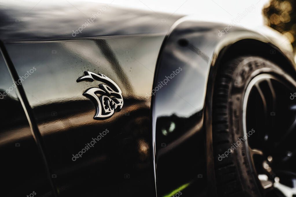 Milan, italy 20 september 2025: dodge hellcat emblem showing on the shiny black fender of a powerful american muscle car, reflecting the warm sunset light