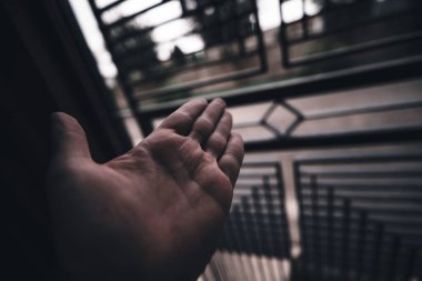 Açık el bulanık parmaklıklardan ışığa doğru uzanır, hapsetme, özlem ve özgürlük için umut, kaçış ve sınırların ötesinde yeni bir başlangıç