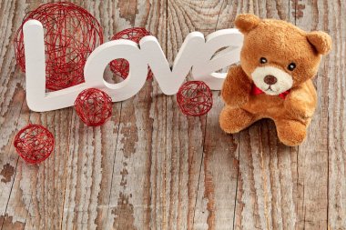 Beyaz aşk işareti ahşap arka planda oyuncak ayı ve takı ile 