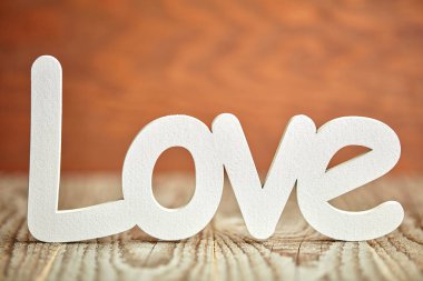 Tahta masa ve kahverengi arka planda beyaz aşk işareti