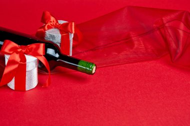 İki hediye ve şarap şişesi ile kırmızı arka plan