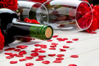 Konfeti ve cam ile beyaz ahşap arka plan üzerinde kırmızı gül ve şarap şişesi tomurcukları