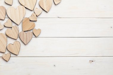 Beyaz ahşap arka plan üzerinde farklı boyutta kalp figürleri 