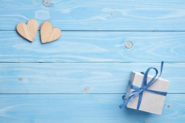 Gümüş hediye ve kırmızı kurdele ile mavi ahşap arka plan