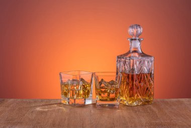 Alkol ile eski moda cam ve carafe, sıcak viski içecek, koyu turuncu arka plan ve ahşap