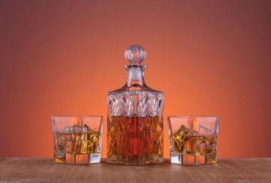 Alkol ile eski moda cam ve carafe, sıcak viski içecek, koyu turuncu arka plan ve ahşap