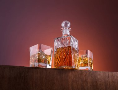 Alkol ile eski moda cam ve carafe, sıcak viski içecek, koyu turuncu arka plan ve ahşap