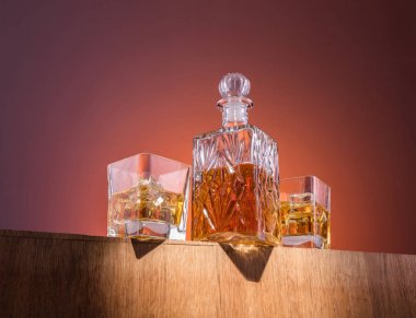Alkol ile eski moda cam ve carafe, sıcak viski içecek, koyu turuncu arka plan ve ahşap