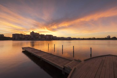 Emerald göl şehir merkezine mesafe ile ön planda iskelesi ile kırmızı, turuncu günbatımı. 