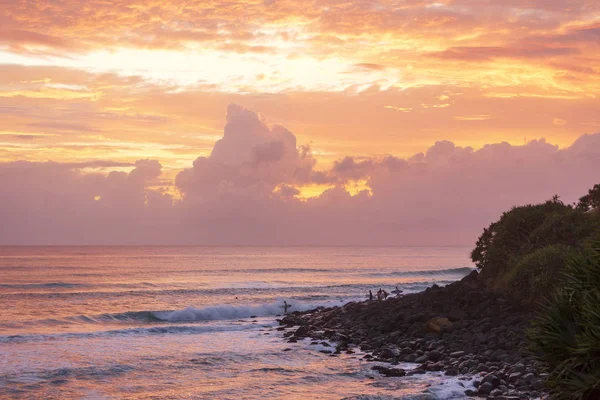 Burleigh Heads, Gold Coast Avustralya Avustralya kayaların üzerinde duran sörfçü ile renkli gündoğumu