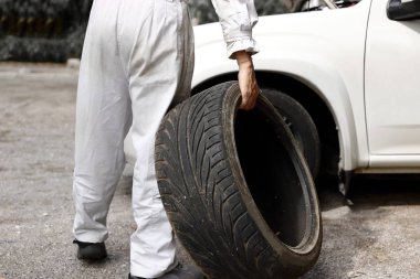 Arabasını garaj arka plan tamir için Tekdüzen holding lastik profesyonel otomotiv mekanik. Oto Tamir Servisi.
