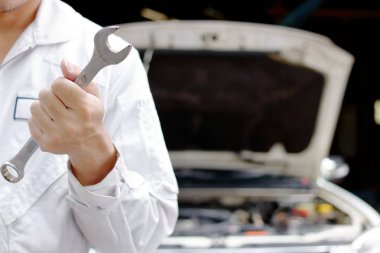 Üniformalı anahtarı açık kukuleta ile onarım garajda holding profesyonel genç mekanik adam. Araba sigortası kavramı.