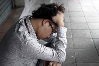 Yüzünü elleriyle kapsayan karışık anksiyete genç Asya iş adamı arka görünümü.