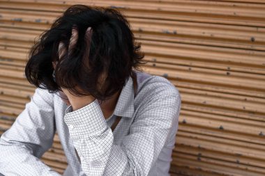 Oturma ve alın elleri ile dokunarak endişeli hayal kırıklığına uğramış genç Asya iş adamı.