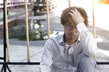 Yüzünü elleriyle kapsayan karışık yorgun Asya iş adamı.