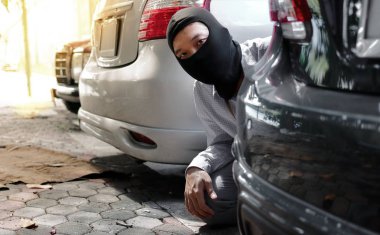 Siyah kar maskeli bir hırsız arabaya girmeye çalışıyor. Suç konsepti.