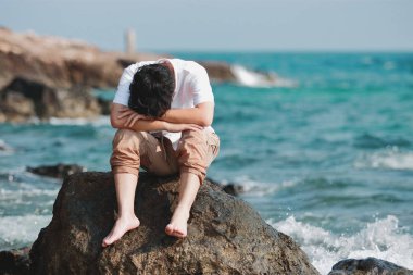 Yalnız üzücü Genç Asyalı adam doğal deniz sahilinde hayal kırıklığına duygu.