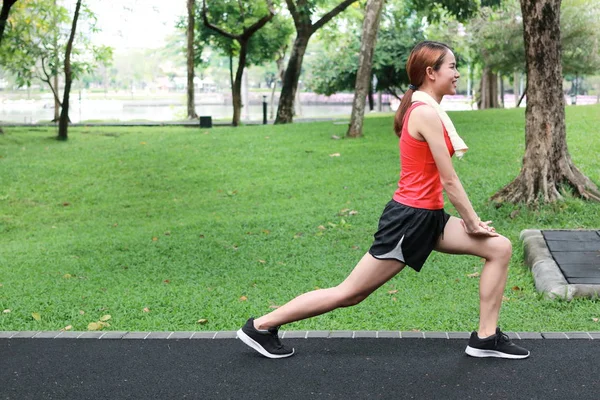 Önce bacaklarını germe sağlıklı Asyalı kadın yan görünüm parkta çalıştırın. Fitness ve egzersiz kavramı.