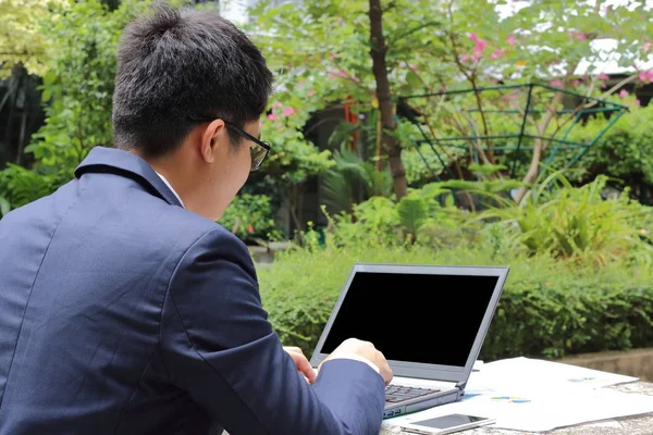 Yakın çekim yakışıklı genç iş adamı dikiz genel doğa arka plan içinde laptop ile çalışma.