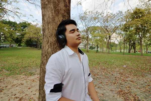 Asiático Joven Escuchando Música Con Auriculares Recostado Árbol Parque Público — Foto de Stock