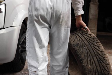 Lastik ve arabasını tamir onarım garaj arka plan için anahtar ile üniformalı otomotiv mekanik.