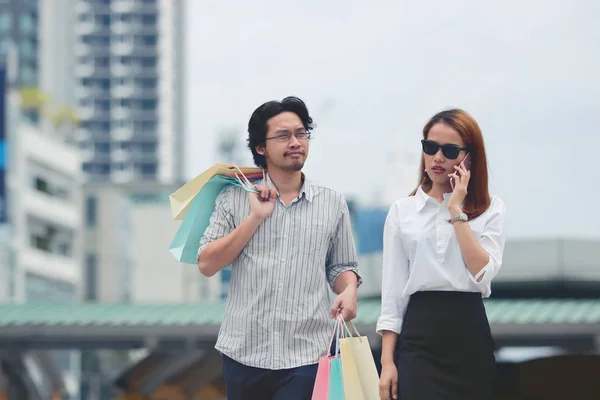 年轻的亚洲夫妇携带五颜六色的购物袋在城市街道上 — 图库照片