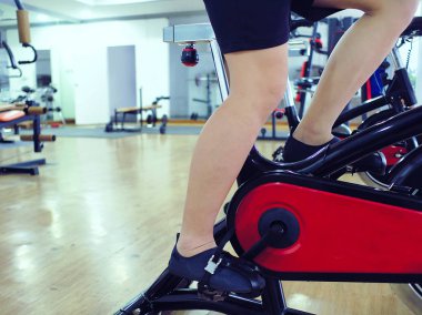 Sağlıklı gencin Bisiklet makine spor salonunda egzersiz bacak resim kırpılmış. Fitness ve egzersiz kavramı