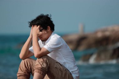 Endişeli Asya adam yüzünü elleri ve baş aşağı bend ile kapsayan depresif