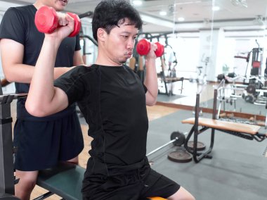 Spor salonunda spor hocasıyla yürüyen sağlıklı bir Asyalı. Fitness ve egzersiz konsepti