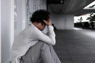 Yerde oturan alnına sinirli stresli Asya adamla yan görünüm eller