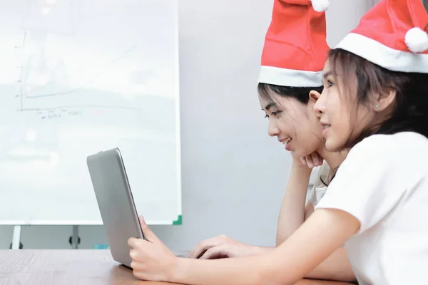 两个欢快的年轻亚洲商界妇女与圣诞老人帽子购物在网上一起在圣诞节假期 物联网概念 — 图库照片