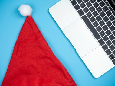 Mavi izole arka plan üzerinde dizüstü ve Santa şapka üstten görünüm.