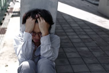 Depresyonda olan, elleri alnında, çok çalışan Asyalı genç bir iş adamı.