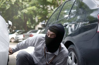 Arabaya girmeye çalışan siyah yün maskeli hırsız