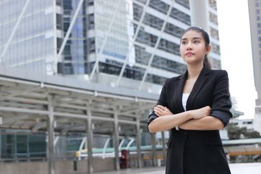 Kendine güvenen genç Asya iş kadını bakarak uzakta dış ofiste.