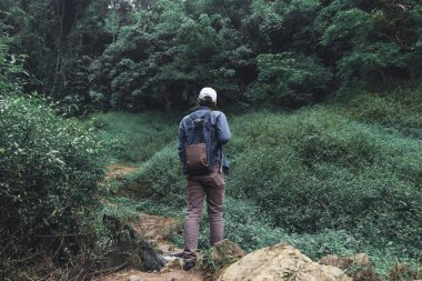 Arkadan görünüşü doğa yeşil dağda hiking Genç Asyalı macera adamı. Seyahat yaşam tarzı ve gevşeme kavramı.