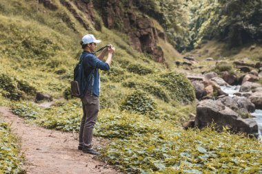 Genç Asian traveler adam açık havada doğal doğa arka planda fotoğraf alıyor. Yaşam tarzı ve gevşeme kavramı.