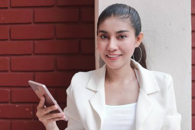 Elinde cep telefonu ile gülümseyen genç Asyalı kadın. Nesnelerin İnterneti kavramı