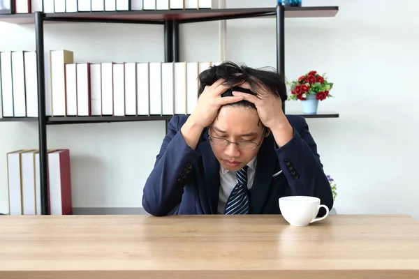 Verwirrt müde junge asiatische Geschäftsmann schließen seine Augen und fühlen Depression am Arbeitsplatz des Büros. — Stockfoto