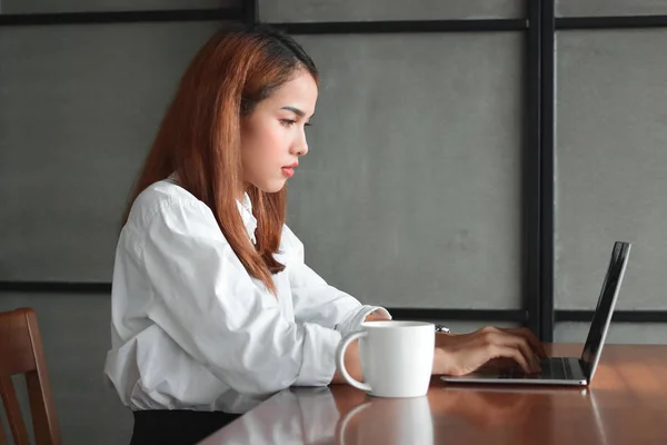 Уверенная в красоте молодая азиатская деловая женщина работает с ноутбуком на рабочем месте офиса . — стоковое фото