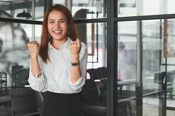 Мягкий фокус улыбающейся молодой азиатской предпринимательницы, поднимающей руки в офисе. Концепция успешной деловой женщины. — стоковое фото