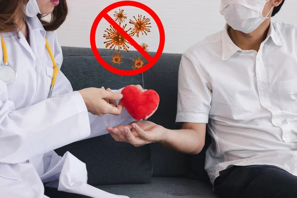 Young Asian female doctor giving red heart patient for encouragement and empathy. Coronavirus flu virus , Covid 19 , Antiviral drugs concept.