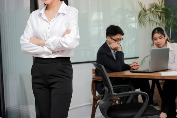 Leadership business woman concept. Cropped image of young Asian businesswoman standing against her colleague in office background.