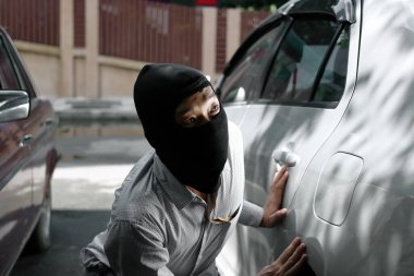 Siyah kar maskeli bir hırsız arabaya girmeye çalışıyor. Suç konsepti.