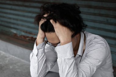 İşsiz, stresli, takım elbiseli Asyalı iş adamı elleri ile yüzünü kapatıyor. Başarısızlık ve işten çıkarma kavramı.
