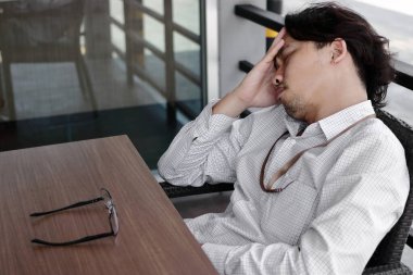 Depresyondaki Asyalı genç iş adamı elleri başının üstünde. İşsizlik ve işten çıkarma kavramı.