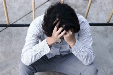 İşsiz ve stresli Asyalı bir iş adamı yerde oturuyor. Başarısızlık ve işten çıkarma kavramı.